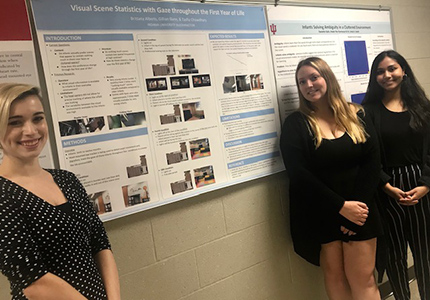3 students in front of their poster