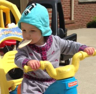 toddler on trike wearing looxcie attached to cap