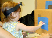 child with head camera putting disc through slot in box